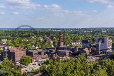 Die Geschichte Zollvereins beginnt in den Pioniertagen des heutigen Ruhrgebiets. Der erste Schacht wurde 1847 abgeteuft, vier Jahre später die erste Kohle gefördert: Vier weitere Anlagen entstanden, die letzte war die Schachtanlage Zollverein XII,  die ab 1932 die Förderung der gesamten Zollverein-Kohle zentral übernahm. 

Die Gebäude der 1928 bis 1932 im Stil der „Neuen Sachlichkeit“ nach Entwürfen der Architekten Fritz Schupp und Martin Kremmer gebauten Anlage sind nach dem Prinzip „Form follows Function“ zum optimalen Ablauf der Kohleförderung und -aufbereitung angeordnet. Trotz Rekordzahlen wie 12.000 Tagestonnen verwertbarer Steinkohle machte das Ende der Schwerindustrie auch vor Zollverein nicht Halt. Am 23. Dezember 1986 fuhr die letzte Schicht ein. An diesem Tag stand die Zeche bereits unter Denkmalschutz, 1990 begannen die Sanierungsarbeiten und seit 2001 sind Zeche und Kokerei Zollverein UNESCO-Welterbe. Mit dem Denkmalpfad ZOLLVEREIN®, dem Ruhr Museum und dem Red Dot Design Museum sind auf Schacht XII drei der beliebtesten Touristenziele der Region angesiedelt. Das Doppelbock-Fördergerüst der Schachtanlage ist heute ein Wahrzeichen für das gesamte Ruhrgebiet. 

Ort: Areal A [Schacht XII]
