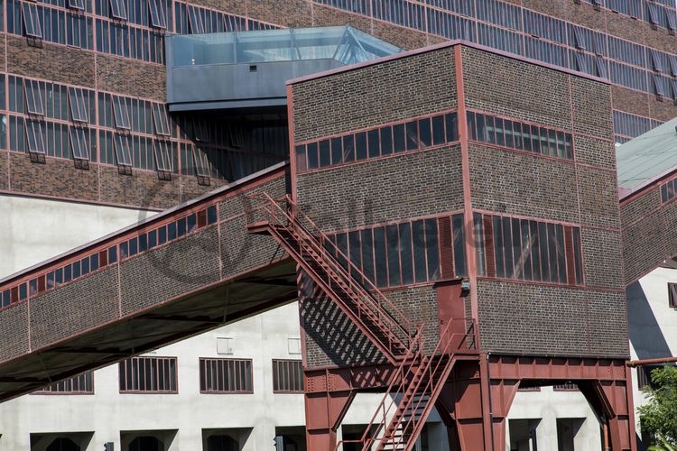 Das größte Übertagegebäude auf Zollverein, die Kohlenwäsche [A14], war zu Betriebszeiten eine Riesenmaschine, die täglich 23.000 Tonnen Rohkohle sortierte und klassierte. Von 2003 bis 2006 wurde sie von dem Office for Metropolitan Architecture (OMA) unter Leitung von Rem Koolhaas und dem Essener Büro Böll & Krabel umfassend saniert. Die Kohlenwäsche ist zentrale Anlaufstelle für Besucher sowie Museumsgebäude des 2010 eröffneten Ruhr Museums und des Portals der Industriekultur. Die oberen Etagen gehören mit den authentisch erhaltenen Übertageanlagen zum Denkmalpfad ZOLLVEREIN®. Auf dem Dach der Kohlenwäsche sind zwei Aussichtsplattformen installiert, die einen Rundblick auf das Gelände und die Region bieten. 

Die beiden 58 Meter langen Rolltreppen an der Kohlenwäsche [A14] befördern die Besucher direkt auf die 24-Meter-Ebene der Kohlenwäsche und von dort wieder nach unten. Die beiden Sonderanfertigungen von ThyssenKrupp Elevator – eine für die Auffahrt, eine für die Abfahrt – orientieren sich an den historischen Bandbrücken. Das Konzept wurde von dem Rotterdamer Office for Metropolitan Architecture (OMA) entwickelt. Eine Fahrt auf einer der beiden höchsten freistehenden Fahrtreppen Deutschlands dauert 90 Sekunden. Highlight: Bei Dunkelheit leuchten die Fahrtreppen orangerot.

Die diagonal und waagerecht zwischen den Gebäuden verlaufenden Bandbrücken sind fester Bestandteil der Gebäudeensembles von Zeche und Kokerei Zollverein. In ihrem Inneren befinden sich Bänder, auf denen die Rohkohle bzw. Kokskohle oder Koks zu den einzelnen Verarbeitungsstufen transportiert wurden. Sie illustrieren sozusagen den Weg der Kohle, neben dem Transportband verlaufen  schmale Wege und Treppe für die Bergleute. Im Gegensatz zu den reinen Mannschaftsbrücken sind die Bandbrücken aus Stahlskelettbauweise mit parallel verlaufenden Fensterbändern geschlossen. 

Ort: Areal A [Schacht XII], Kohlenwäsche [A14]
