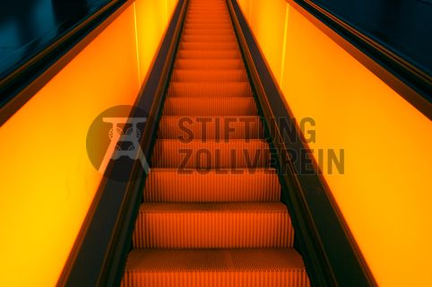 Die beiden 58 Meter langen Rolltreppen an der Kohlenwäsche [A14] befördern die Besucher direkt auf die 24-Meter-Ebene der Kohlenwäsche und von dort wieder nach unten. Die beiden Sonderanfertigungen von ThyssenKrupp Elevator – eine für die Auffahrt, eine für die Abfahrt – orientieren sich an den historischen Bandbrücken. Das Konzept wurde von dem Rotterdamer Office for Metropolitan Architecture (OMA) entwickelt. Eine Fahrt auf einer der beiden höchsten freistehenden Fahrtreppen Deutschlands dauert 90 Sekunden. Highlight: Bei Dunkelheit leuchten die Fahrtreppen orangerot.

Ort: Areal A [Schacht XII], Kohlenwäsche [A14]