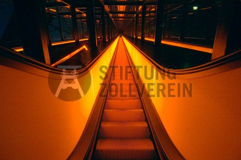 Die beiden 58 Meter langen Rolltreppen an der Kohlenwäsche [A14] befördern die Besucher direkt auf die 24-Meter-Ebene der Kohlenwäsche und von dort wieder nach unten. Die beiden Sonderanfertigungen von ThyssenKrupp Elevator – eine für die Auffahrt, eine für die Abfahrt – orientieren sich an den historischen Bandbrücken. Das Konzept wurde von dem Rotterdamer Office for Metropolitan Architecture (OMA) entwickelt. Eine Fahrt auf einer der beiden höchsten freistehenden Fahrtreppen Deutschlands dauert 90 Sekunden. Highlight: Bei Dunkelheit leuchten die Fahrtreppen orangerot.

Ort: Areal A [Schacht XII], Kohlenwäsche [A14]