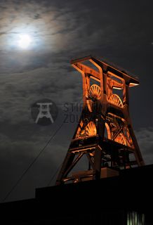 Die Geschichte Zollvereins beginnt in den Pioniertagen des heutigen Ruhrgebiets. Der erste Schacht wurde 1847 abgeteuft, vier Jahre später die erste Kohle gefördert: Vier weitere Anlagen entstanden, die letzte war die Schachtanlage Zollverein XII,  die ab 1932 die Förderung der gesamten Zollverein-Kohle zentral übernahm. 

Die Gebäude der 1928 bis 1932 im Stil der „Neuen Sachlichkeit“ nach Entwürfen der Architekten Fritz Schupp und Martin Kremmer gebauten Anlage sind nach dem Prinzip „Form follows Function“ zum optimalen Ablauf der Kohleförderung und -aufbereitung angeordnet. Trotz Rekordzahlen wie 12.000 Tagestonnen verwertbarer Steinkohle machte das Ende der Schwerindustrie auch vor Zollverein nicht Halt. Am 23. Dezember 1986 fuhr die letzte Schicht ein. An diesem Tag stand die Zeche bereits unter Denkmalschutz, 1990 begannen die Sanierungsarbeiten und seit 2001 sind Zeche und Kokerei Zollverein UNESCO-Welterbe. Mit dem Denkmalpfad ZOLLVEREIN®, dem Ruhr Museum und dem Red Dot Design Museum sind auf Schacht XII drei der beliebtesten Touristenziele der Region angesiedelt. Das Doppelbock-Fördergerüst der Schachtanlage ist heute ein Wahrzeichen für das gesamte Ruhrgebiet. 

Das 55 Meter hohe Doppelbock-Fördergerüst ist das Wahrzeichen der Zeche Zollverein, der Stadt Essen und der gesamten Region: Die als Doppelstrebengerüst in Vollwandbauweise konstruierte Förderanlage ermöglichte eine doppelte Fördermechanik, mittels derer die doppelte Menge Förderwagen bzw. Fördergefäße transportiert werden konnten. Zollverein Schacht XII galt zu Betriebszeiten als die leistungsstärkste Zeche der Welt. 250 Stufen führen auf die oberste Plattform des Gerüstes, deren Seilscheiben sich auch heute noch drehen: Der Schacht wird heute von der RAG AG für die zentrale Wasserhaltung genutzt.

Areal A [Schacht XII], Fördergerüst [A1]