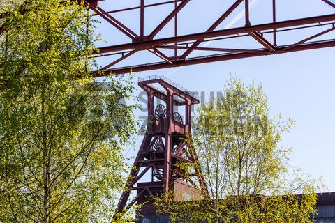 Das 55 Meter hohe Doppelbock-Fördergerüst ist das Wahrzeichen der Zeche Zollverein, der Stadt Essen und der gesamten Region: Die als Doppelstrebengerüst in Vollwandbauweise konstruierte Förderanlage ermöglichte eine doppelte Fördermechanik. Dadurch konnte die doppelte Menge an Förderwagen bzw. Fördergefäßen transportiert werden. Zollverein Schacht XII galt zu Betriebszeiten als die leistungsstärkste Zeche der Welt. 250 Stufen führen auf die oberste Plattform des Gerüstes, deren Seilscheiben sich auch heute noch manchmal drehen: Der Schacht wird von der RAG AG für die zentrale Wasserhaltung genutzt.

Areal A [Schacht XII], Fördergerüst [A1]