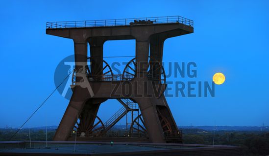 Das 55 Meter hohe Doppelbock-Fördergerüst ist das Wahrzeichen der Zeche Zollverein, der Stadt Essen und der gesamten Region: Die als Doppelstrebengerüst in Vollwandbauweise konstruierte Förderanlage ermöglichte eine doppelte Fördermechanik. Dadurch konnte die doppelte Menge an Förderwagen bzw. Fördergefäßen transportiert werden. Zollverein Schacht XII galt zu Betriebszeiten als die leistungsstärkste Zeche der Welt. 250 Stufen führen auf die oberste Plattform des Gerüstes, deren Seilscheiben sich auch heute noch manchmal drehen: Der Schacht wird von der RAG AG für die zentrale Wasserhaltung genutzt.

Areal A [Schacht XII], Fördergerüst [A1]