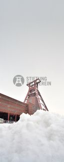Das 55 Meter hohe Doppelbock-Fördergerüst ist das Wahrzeichen der Zeche Zollverein, der Stadt Essen und der gesamten Region: Die als Doppelstrebengerüst in Vollwandbauweise konstruierte Förderanlage ermöglichte eine doppelte Fördermechanik. Dadurch konnte die doppelte Menge an Förderwagen bzw. Fördergefäßen transportiert werden. Zollverein Schacht XII galt zu Betriebszeiten als die leistungsstärkste Zeche der Welt. 250 Stufen führen auf die oberste Plattform des Gerüstes, deren Seilscheiben sich auch heute noch manchmal drehen: Der Schacht wird von der RAG AG für die zentrale Wasserhaltung genutzt.

Areal A [Schacht XII], Fördergerüst [A1]