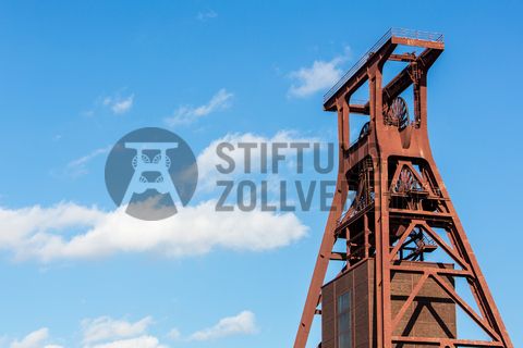 Das 55 Meter hohe Doppelbock-Fördergerüst ist das Wahrzeichen der Zeche Zollverein, der Stadt Essen und der gesamten Region: Die als Doppelstrebengerüst in Vollwandbauweise konstruierte Förderanlage ermöglichte eine doppelte Fördermechanik. Dadurch konnte die doppelte Menge an Förderwagen bzw. Fördergefäßen transportiert werden. Zollverein Schacht XII galt zu Betriebszeiten als die leistungsstärkste Zeche der Welt. 250 Stufen führen auf die oberste Plattform des Gerüstes, deren Seilscheiben sich auch heute noch manchmal drehen: Der Schacht wird von der RAG AG für die zentrale Wasserhaltung genutzt.

Areal A [Schacht XII], Fördergerüst [A1]